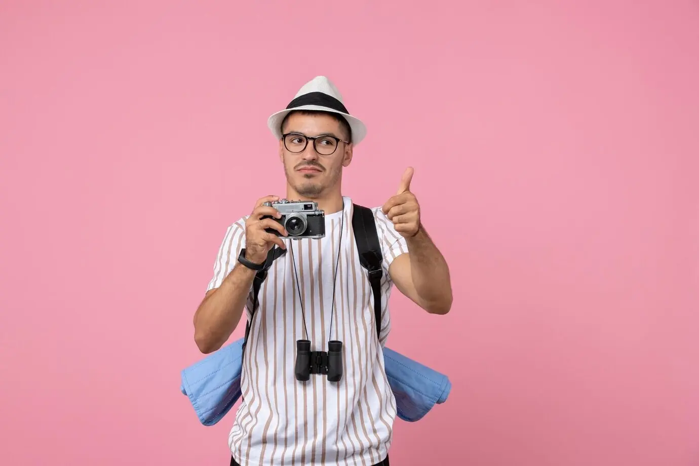 Vorderansicht eines männlichen Touristen mit Kamera vor pinker Wand, Emotion, Farbe.