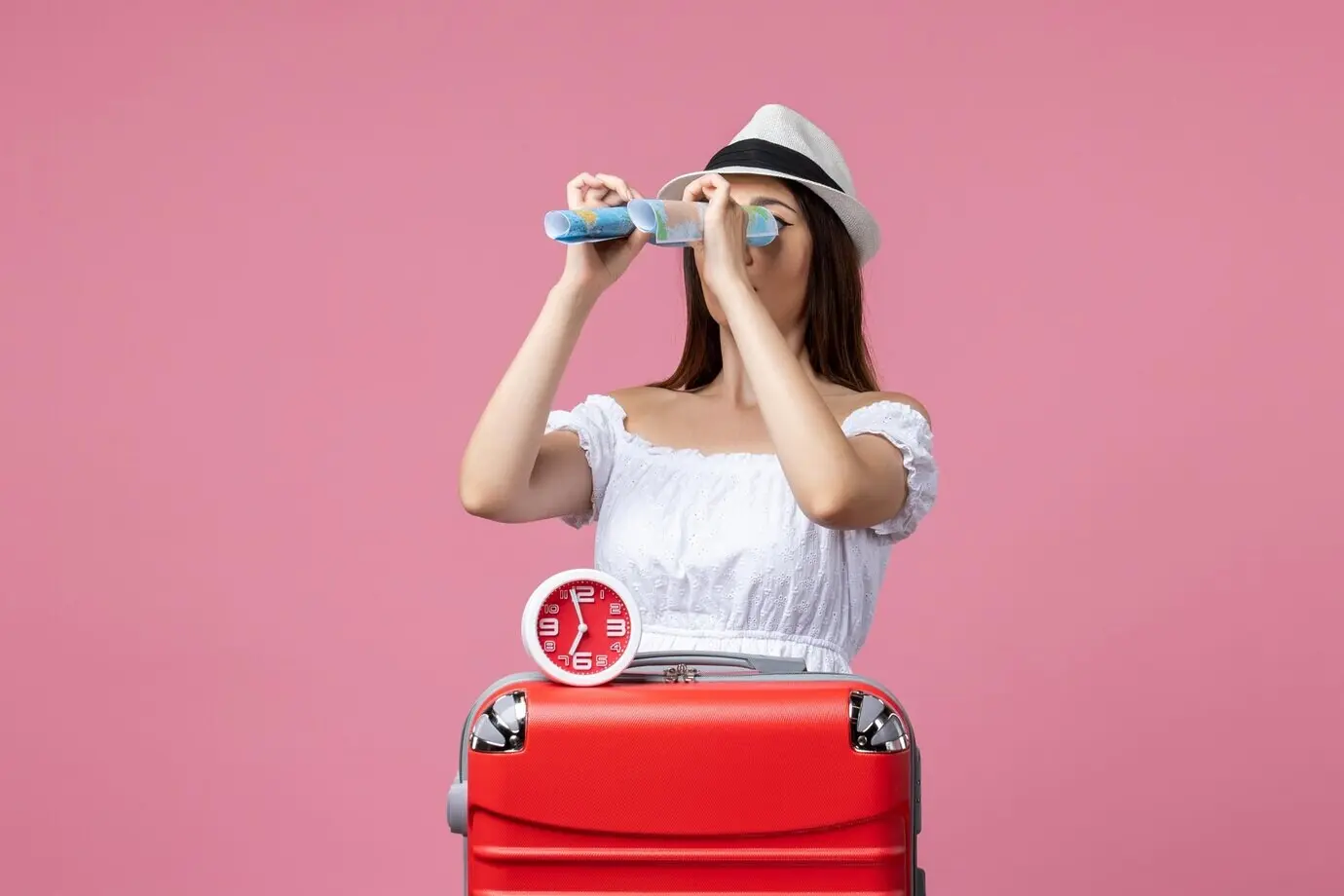 Vorderansicht einer jungen Frau, die im Urlaub vor einer pinken Wand eine Papierkarte hält; Reise, Sommerhitze, Urlaub.