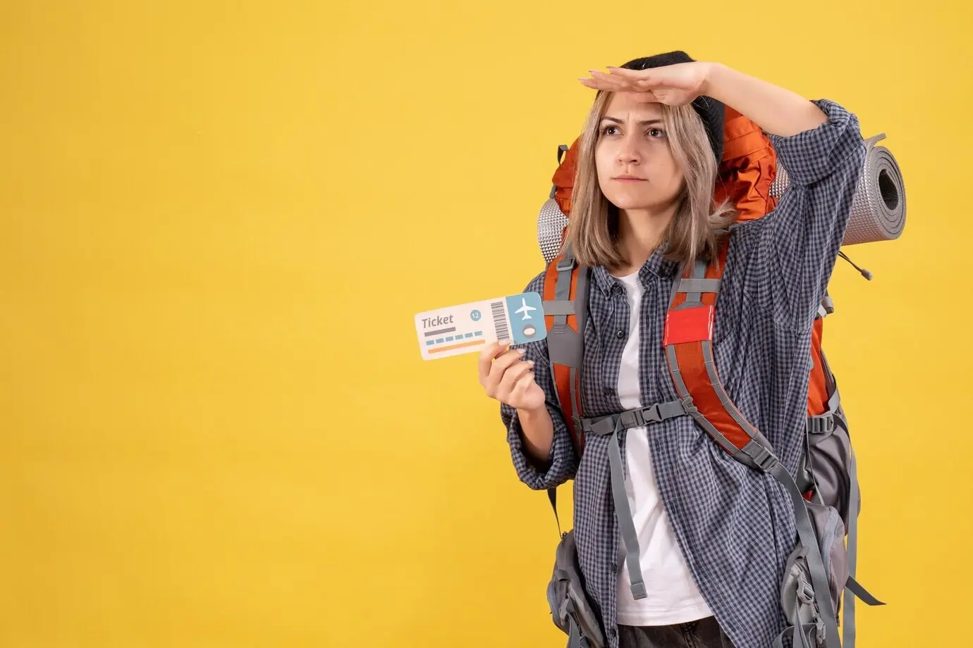 Vorderansicht einer beschäftigten Reisenden mit Rucksack, ein Ticket haltend und beobachtend.